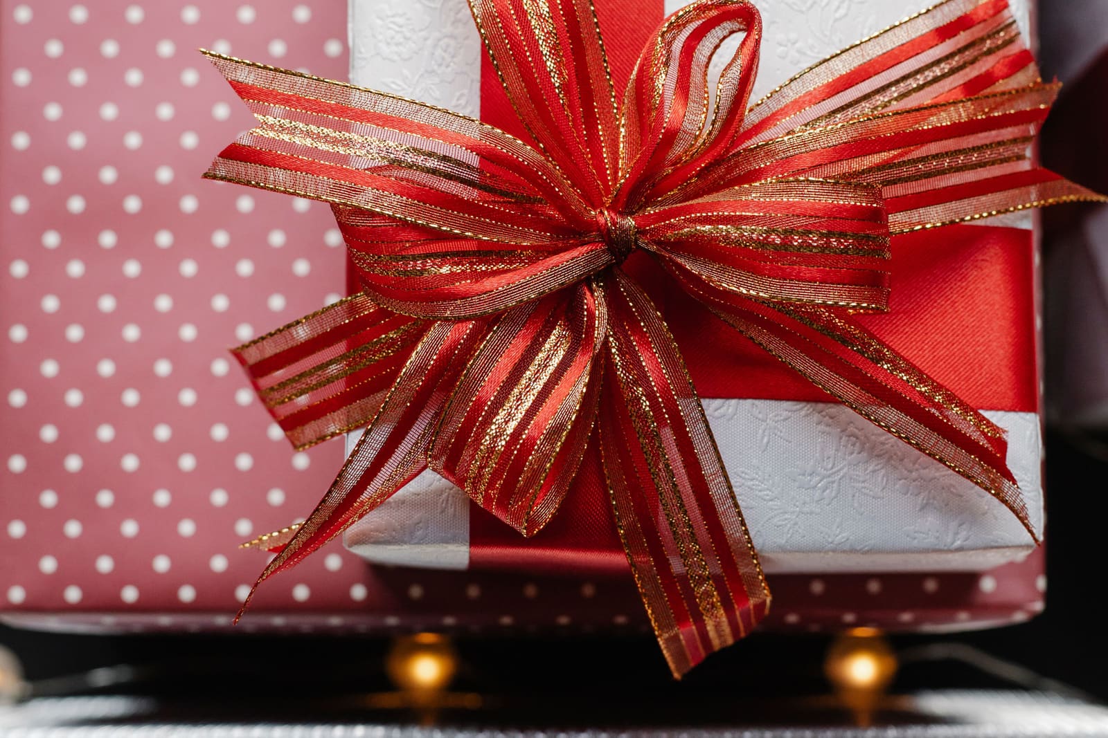 A white wrapped gift box with a large red and gold ribbon bow.